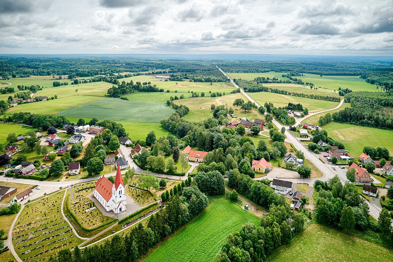Röke by med Röke kyrka (Röke 19:1) i vänsterkant och riksväg 24 som går rakt genom byn och försvinner i skogen i fjärran.