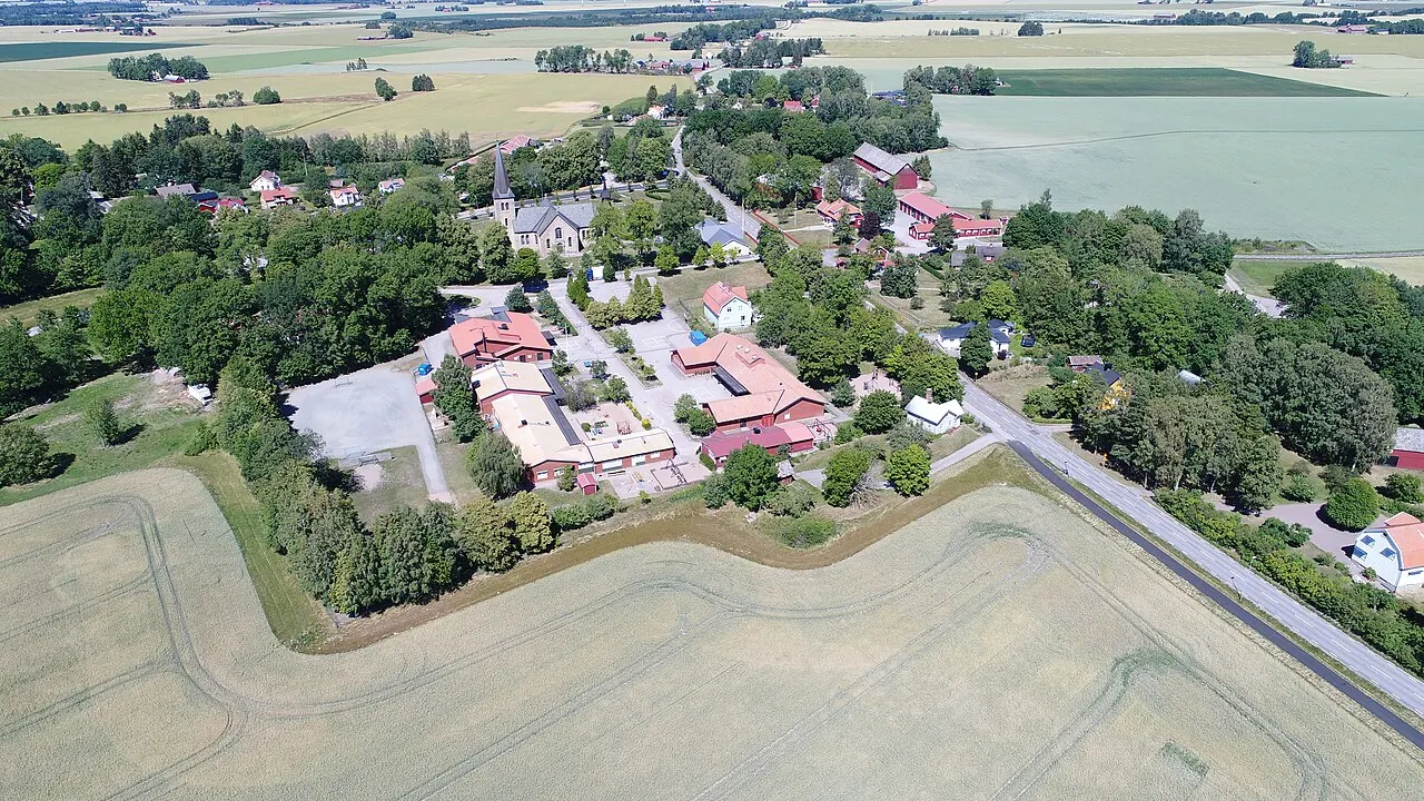 Saleby tätort i Lidköpings kommun från söder. Salebyskolan syns närmast i bild och Saleby kyrka strax bakom. Vägen till höger i bild är den…